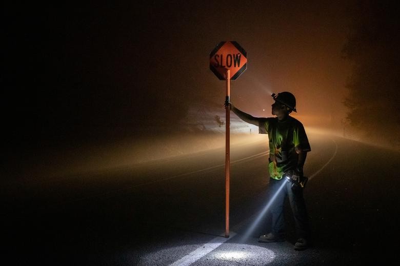Bryan Alvarez holds a sign for oncoming traffic as utility workers repair power lines in the aftermath of the Obenchain Fire in Eagle Point, Oregon. REUTERS/Adrees Latif    